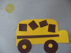 a paper cut out of a yellow school bus on a gray surface with the sun above it