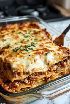 a casserole dish with meat, cheese and sauce in it on a table