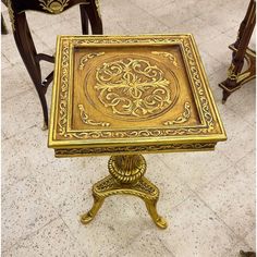 an ornately decorated table with gold paint on it's top and legs, sits in the middle of a tiled floor