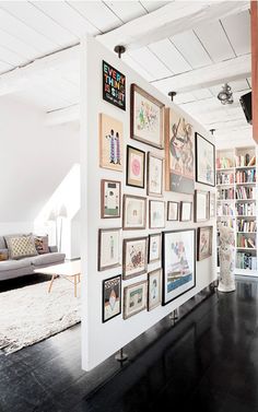 a living room filled with lots of framed pictures on the wall next to a couch