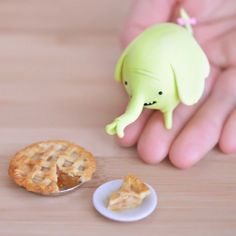 a hand holding a small plastic elephant figurine next to a slice of pie