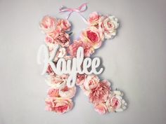 the word kaylee spelled in white letters surrounded by pink flowers on a gray background