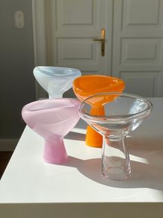 three different colored vases sitting on top of a white table next to a door