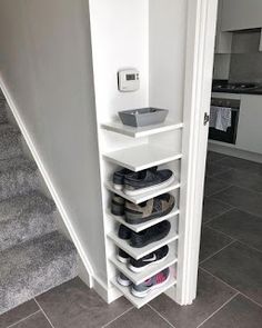 there is a shelf with shoes on it in the corner next to stairs and carpet