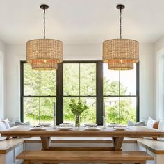 a dining room table with benches and two lights hanging from the ceiling over it's windows