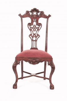 an ornate wooden chair with red velvet upholstered seat and back, against a white background