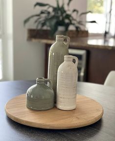 three vases sitting on top of a wooden plate