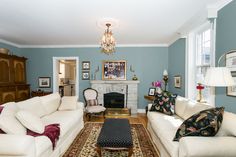 a living room filled with furniture and a fire place under a chandelier in front of a fireplace