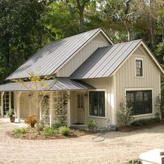 a white house with a metal roof surrounded by trees