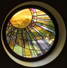 a round stained glass window with mountains in the background and sunlight coming through it's center