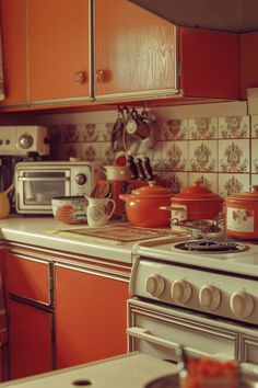 an orange kitchen with pots and pans on the stove top next to the oven