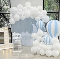 balloons are arranged on the floor in front of a large number one sign and chair