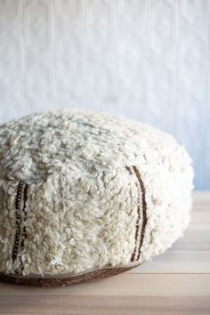 a close up of a white hat on a wooden table with a wall in the background