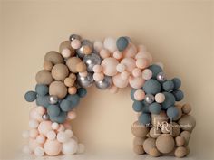 balloons are arranged in the shape of an arch on a table with a beige background