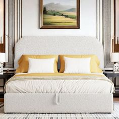 a large bed sitting in a bedroom next to two lamps and a painting on the wall