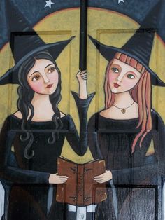 two women wearing witches hats are holding an open book in front of a door with the moon and stars painted on it