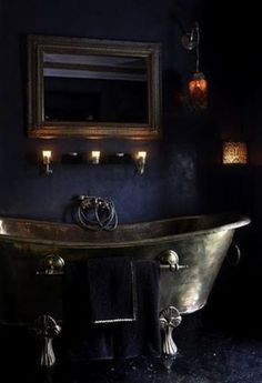 an old fashioned bathtub in a bathroom with candles on the wall and blue walls