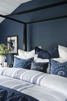 a bedroom with blue walls and white bedding, along with pillows on the headboard