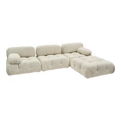 a white sectional couch with pillows on it and a footstool in the middle