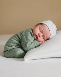 a baby sleeping on top of a white pillow