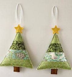 two christmas trees made out of fabric and wooden sticks with yellow stars on each one