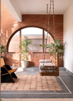 a room with a swing chair and potted plants