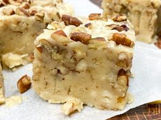 a piece of cake with nuts on it sitting on top of wax paper next to a knife