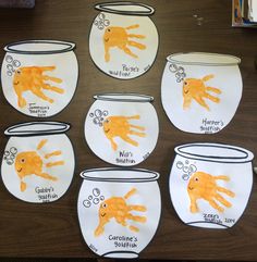 six handprints on white paper with orange and yellow hands in fishbowes