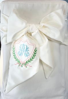 the back of a white chair with a bow on it's belt and monogrammed initials