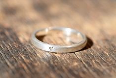 a silver ring sitting on top of a wooden table next to a piece of wood