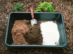 a garden with dirt, grass and soil in a plastic container next to a plant