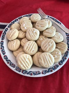 a plate full of cookies with icing on them next to a fork and knife