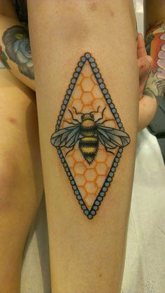 a tattoo on someone's leg with a bee in the center and honeycombs around it