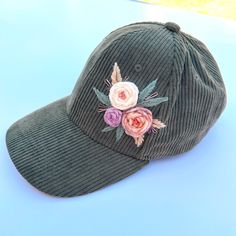 a green hat with flowers on it sitting on a blue table next to a white wall