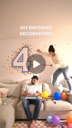 a man and woman are playing video games in a living room with balloons on the floor