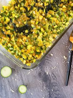 a casserole dish with zucchini, cheese and other toppings on a wooden table