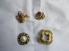 "Two vintage scarf rings and two pins.  You choose at checkout which ones you would like.  In excellent shape. 1 - The gold tone watering can is approximately 1 1/2\" long and a faux pearl dangles from the spout. 2 - An USA pin with the five circles intertwined.  This is approximately 1 1/4\" wide. 3 - A faux pearl scarf ring.  It is approximately 1 1/2\" round. 4 - Gold tone square scarf ring.  It is approximately 1 3/4\" square. Thank you for looking." Saranac Lake Ny, Dowsing Rods, Saranac Lake, Scarf Rings, Scarf Pin, Square Ring, Vintage Scarf, Watering Can, Square Scarf