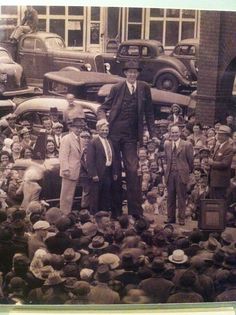 an old black and white photo of a man standing in front of a group of people