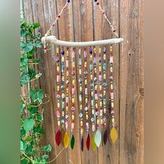 a wind chime hanging from a wooden fence next to a green plant with leaves