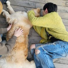 two people are laying on the ground with their dogs and one is holding his head