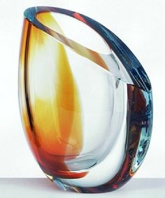 a glass vase with an orange and blue swirl on the inside, sitting on a white surface