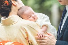 a woman holding a baby in her arms while she is wearing a suit and tie