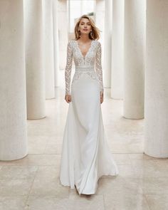 a woman in a white wedding dress is walking through columns