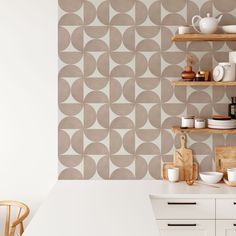 a kitchen with white counters and shelves filled with dishes on top of them next to a wall that has circles painted on it