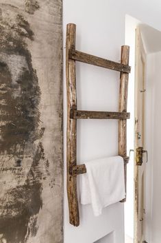 a towel rack made out of wooden sticks in a bathroom with a painting on the wall