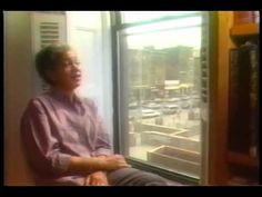 a man sitting in front of a window looking out at the city outside his house