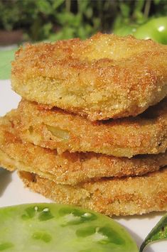 some fried food on a white plate next to green beans and a pickle leaf