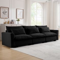 a black couch sitting on top of a white rug in a living room next to a window