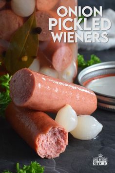 there are two sausages on the table next to some onions and carrots in a jar