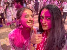 two girls with pink paint on their faces posing for the camera in front of a crowd